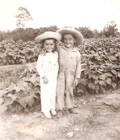 Sepia photo of two little farmer kids surrounded by greenery