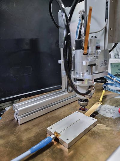 Figure 7: Pick & place measurement setup in laboratory with discharge current sensor (DCS), charging probe, and pick & place head holding a DUT in an elevated position